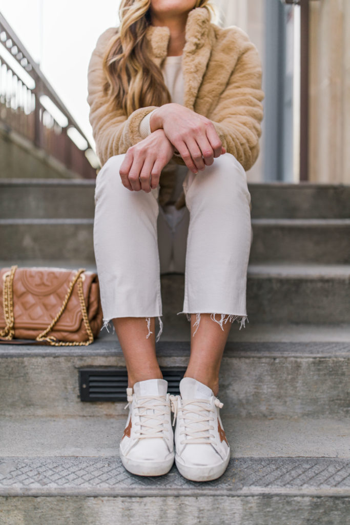 Closeup of golden goose superstar sneakers outfit with white jeans quilted bag faux fur jacket