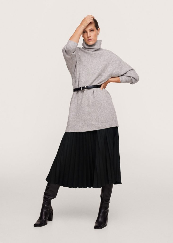 woman wearing gray oversized sweater with black belt knee high boots and black pleated skirt