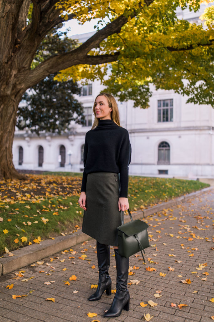woman wearing oversized sweater and skirt outfit with black knee high boots
