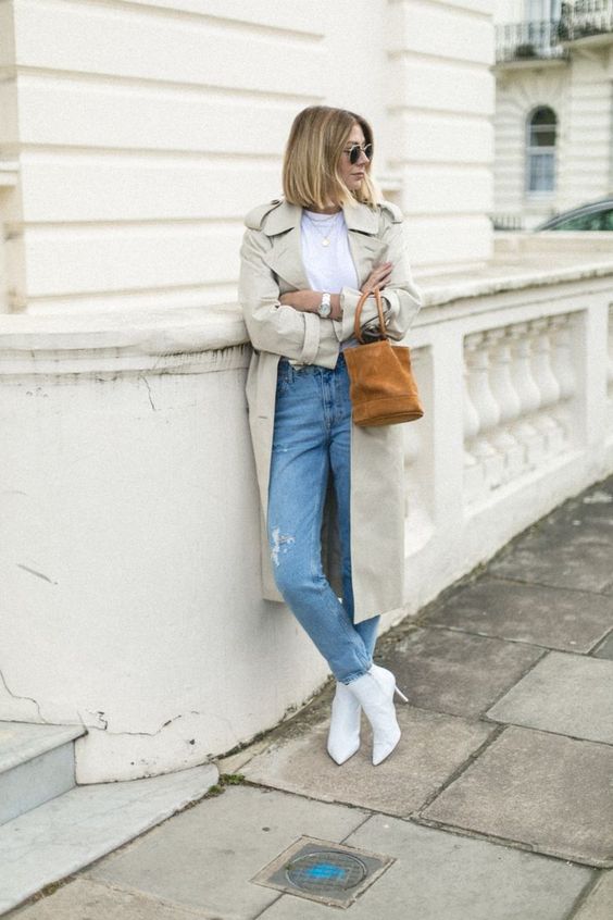 woman wearing white stiletto boots with ripped jeans trench coat white tshirt and brown bag