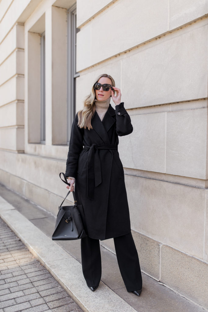 woman wearing turtleneck work outfit with black wool coat and other stories oatmeal turtleneck theory demetria dress pants and schutz heeled booties