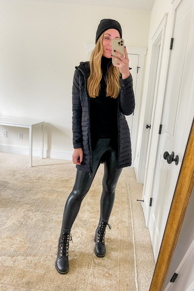 blogueira vestindo roupa de frio com casaco preto puffer leggings de couro sintético botas de combate e gola alta preta