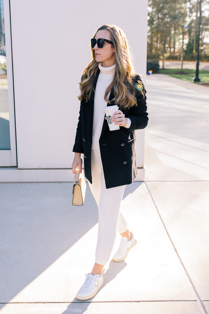 woman wearing casual turtleneck outfit with white turtleneck white joggers double breasted coat and veja v10 sneakers