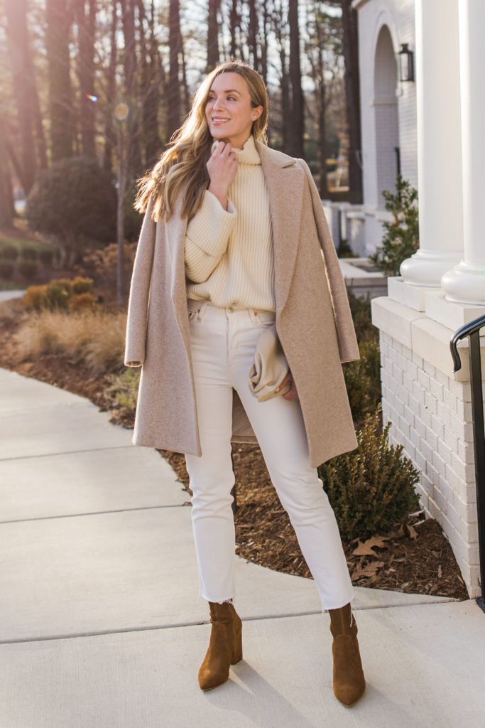 woman wearing oversized cream turtleneck with oatmeal wool coat white straight leg jeans and loeffler randall isla booties