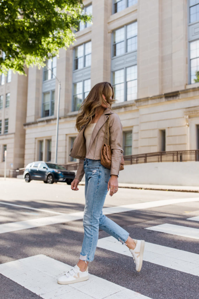 tan moto jacket and white sneakers with light wash jeans