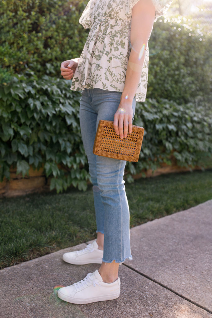 light wash raw hem jeans with sneakers and a floral blouse