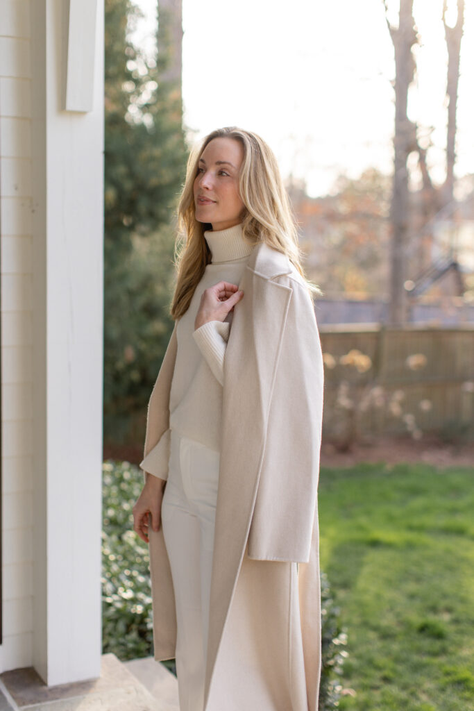 White pants outfit for winter with a white coat, white turtleneck, and neutral pumps